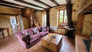 Une pièce rustique avec un canapé en bois, une commode en bois, un téléviseur et une fenêtre avec des rideaux.