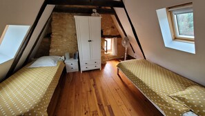 Une chambre avec deux lits, une armoire et un ventilateur.
