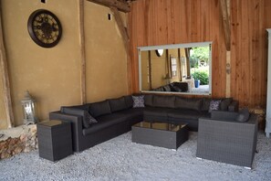 Una sala moderna con un sofá modular, una mesa de centro de vidrio y un espejo grande que refleja la habitación.