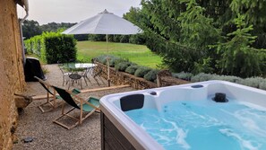 Een whirlpool met een stenen muur en een terras met stoelen en een tafel.