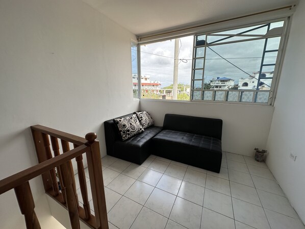 A balcony with a black sofa and a wooden railing. - My place in paradise (Puerto Baquerizo Moreno)