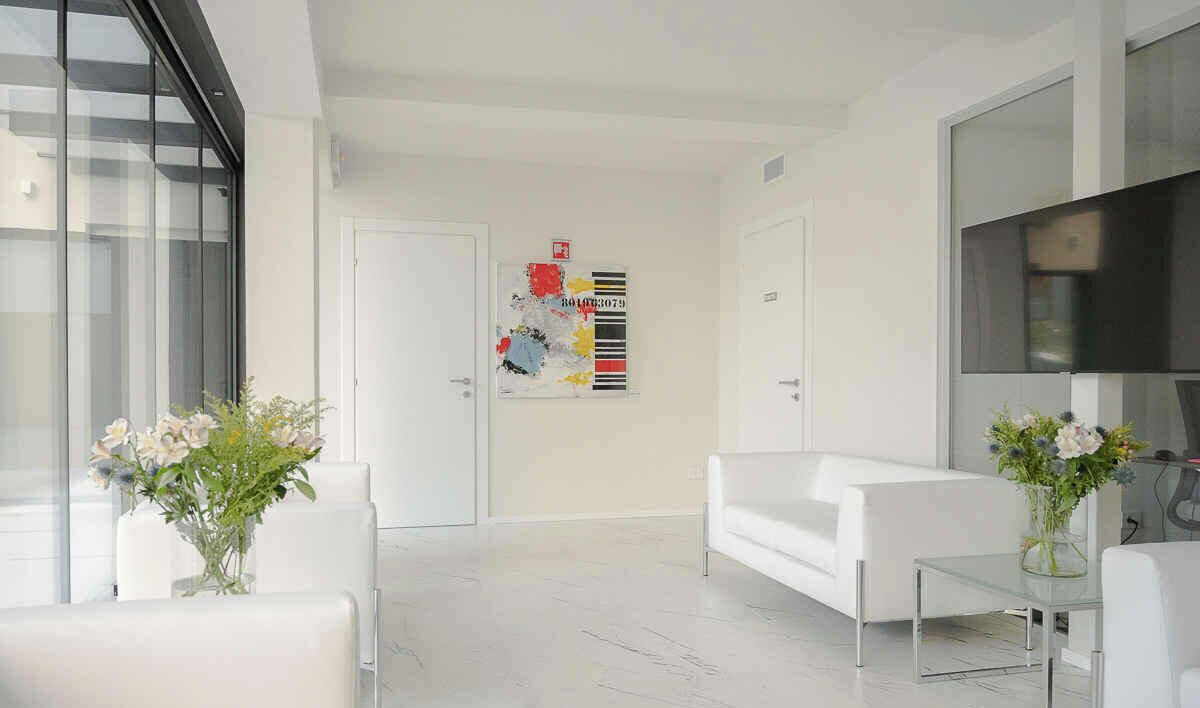 Un salon moderne avec un canapé blanc, une table basse en verre et deux vases ornés de fleurs.