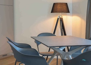 A modern room with a table and chairs, a floor lamp, and a window.