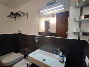 A modern bathroom with a white sink, a mirror, a towel rack, and a toilet. - La Residenza dell'Alloro - Appartamento ACQUA (Palermo)