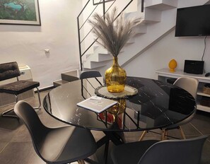 A modern conference room with a round glass table, black chairs, a decorative vase, and a staircase in the background. - La Residenza dell'Alloro - Appartamento ACQUA (Palermo)