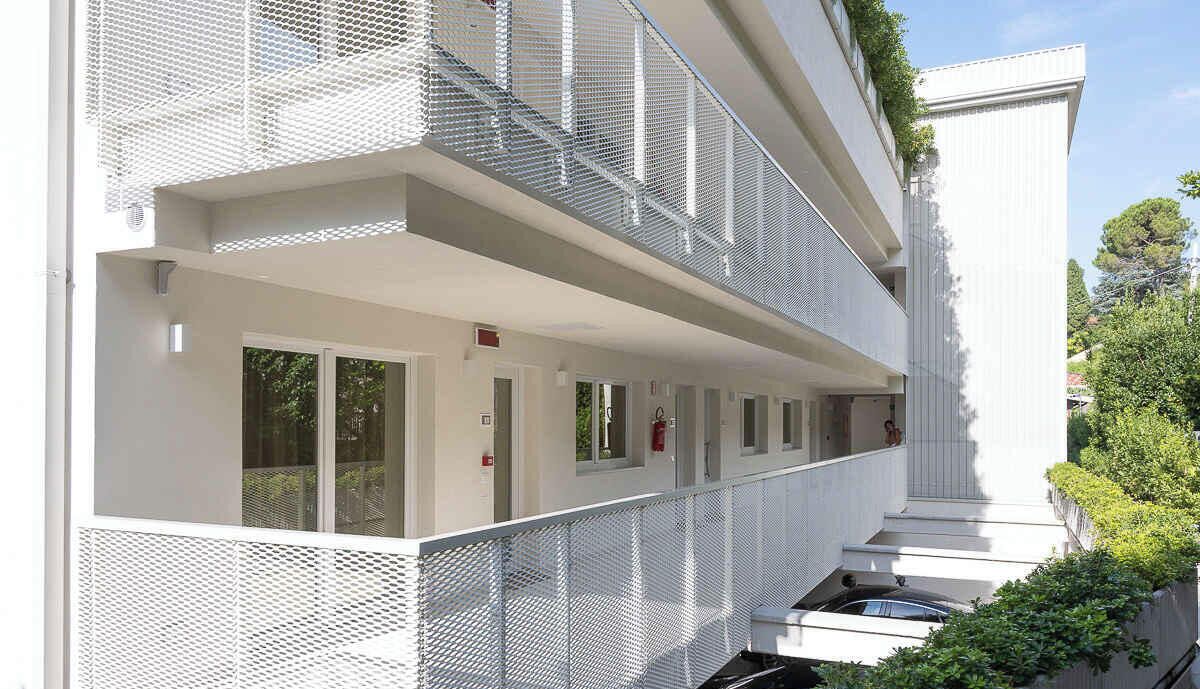 A modern building with a covered outdoor area, multiple windows, and a staircase.