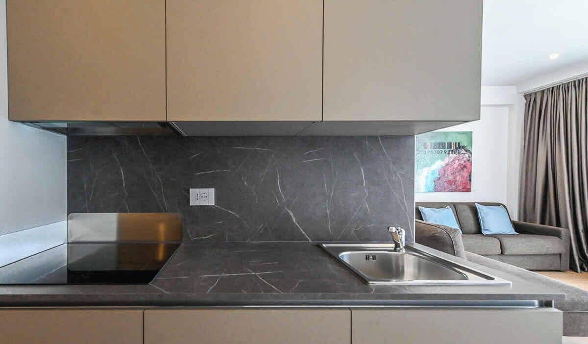 A modern kitchen with a marble countertop, stainless steel sink, and a built-in range hood.