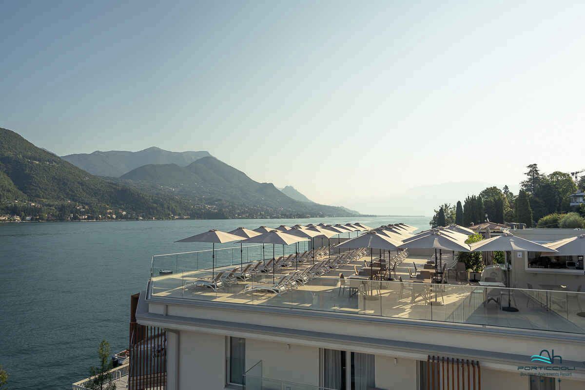 Une terrasse sur le toit, dotée de chaises longues et de parasols, offrant une vue sur un lac et des montagnes.