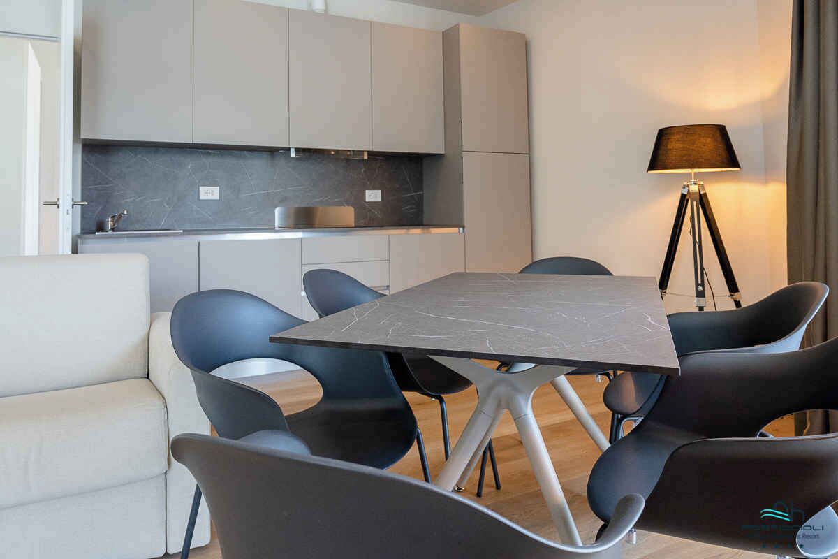 Un espace repas moderne comprenant une table rectangulaire et six chaises, un canapé et un lampadaire.