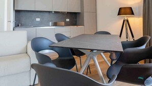Un espace repas moderne comprenant une table rectangulaire et six chaises, un canapé et un lampadaire.