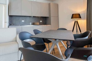Een moderne eethoek met een rechthoekige tafel, zes stoelen, een bank en een vloerlamp.