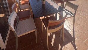 Una zona pranzo all'aperto riparata, con tavolo e sedie, una pianta in vaso e vista sull'oceano.
