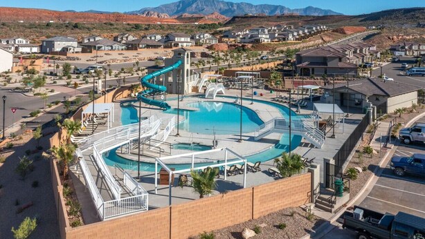 A residential area with a swimming pool, a water slide, and a mountain backdrop.