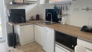 A modern kitchen with a dishwasher, stove, and sink. There is a window providing natural light and a view of the outside.