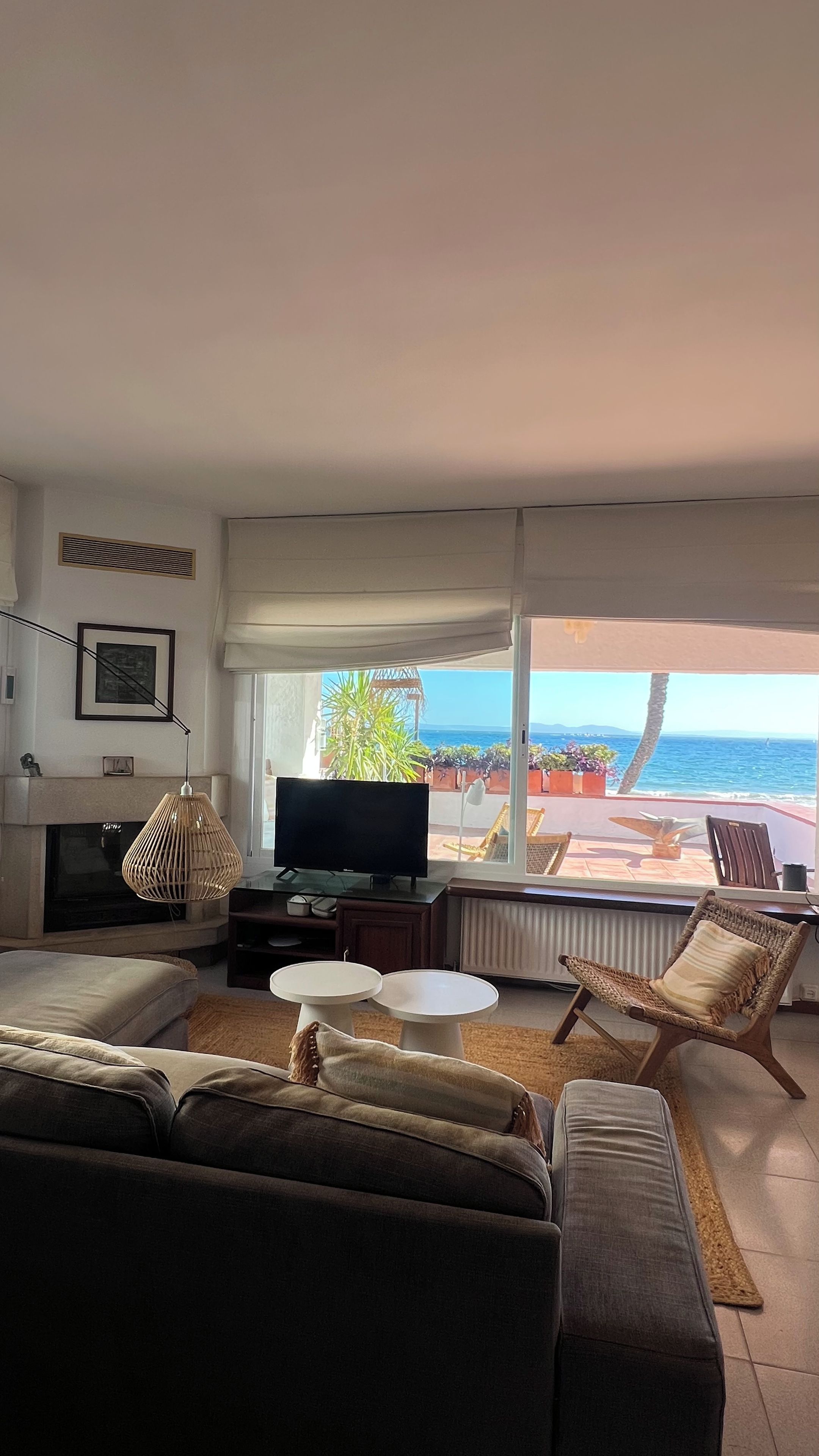A living room with a television, sofas, a coffee table, and a view of the ocean.
