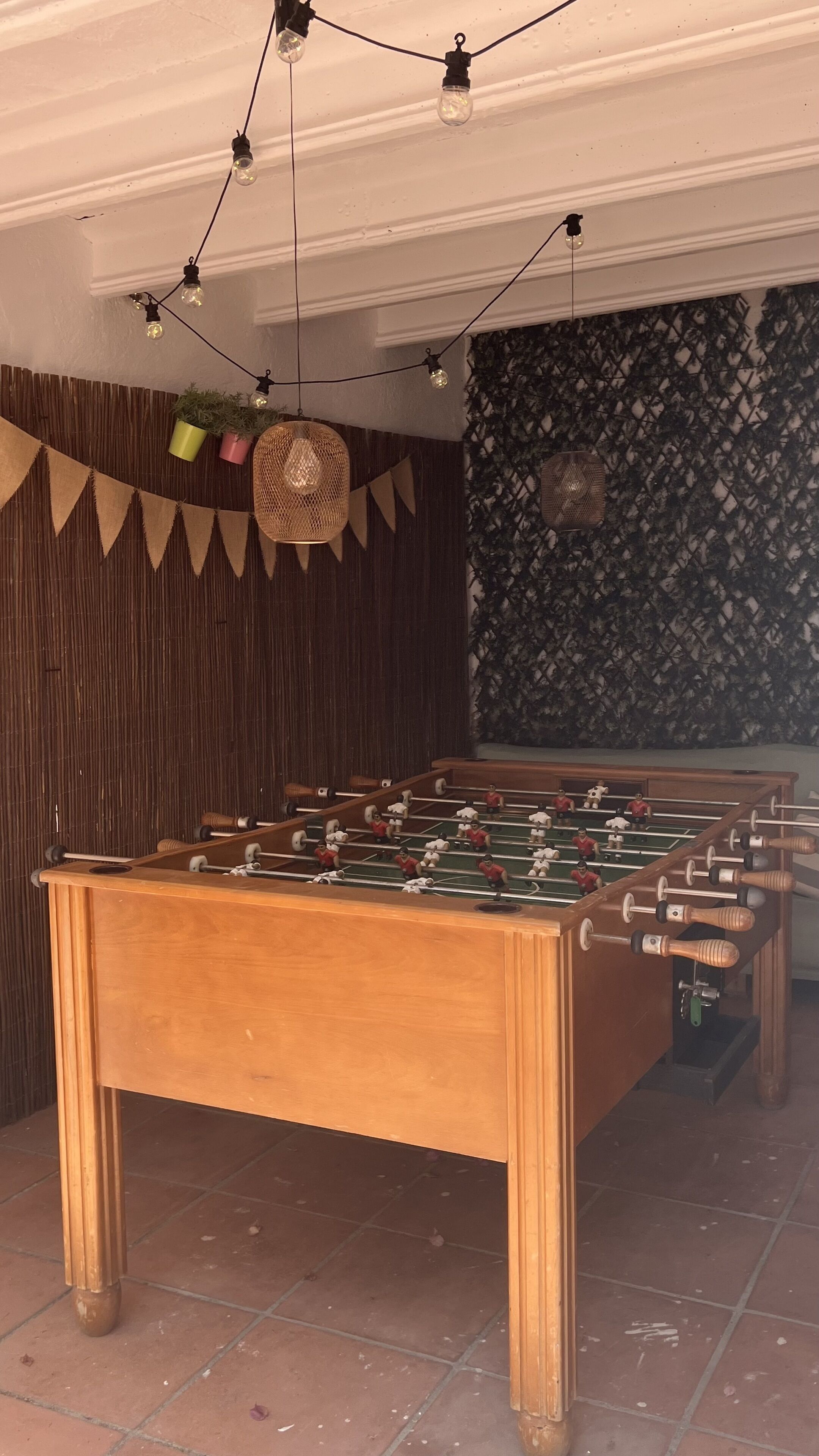 Una mesa de fútbol de mesa en una habitación con pared estampada y panel de madera a la izquierda.