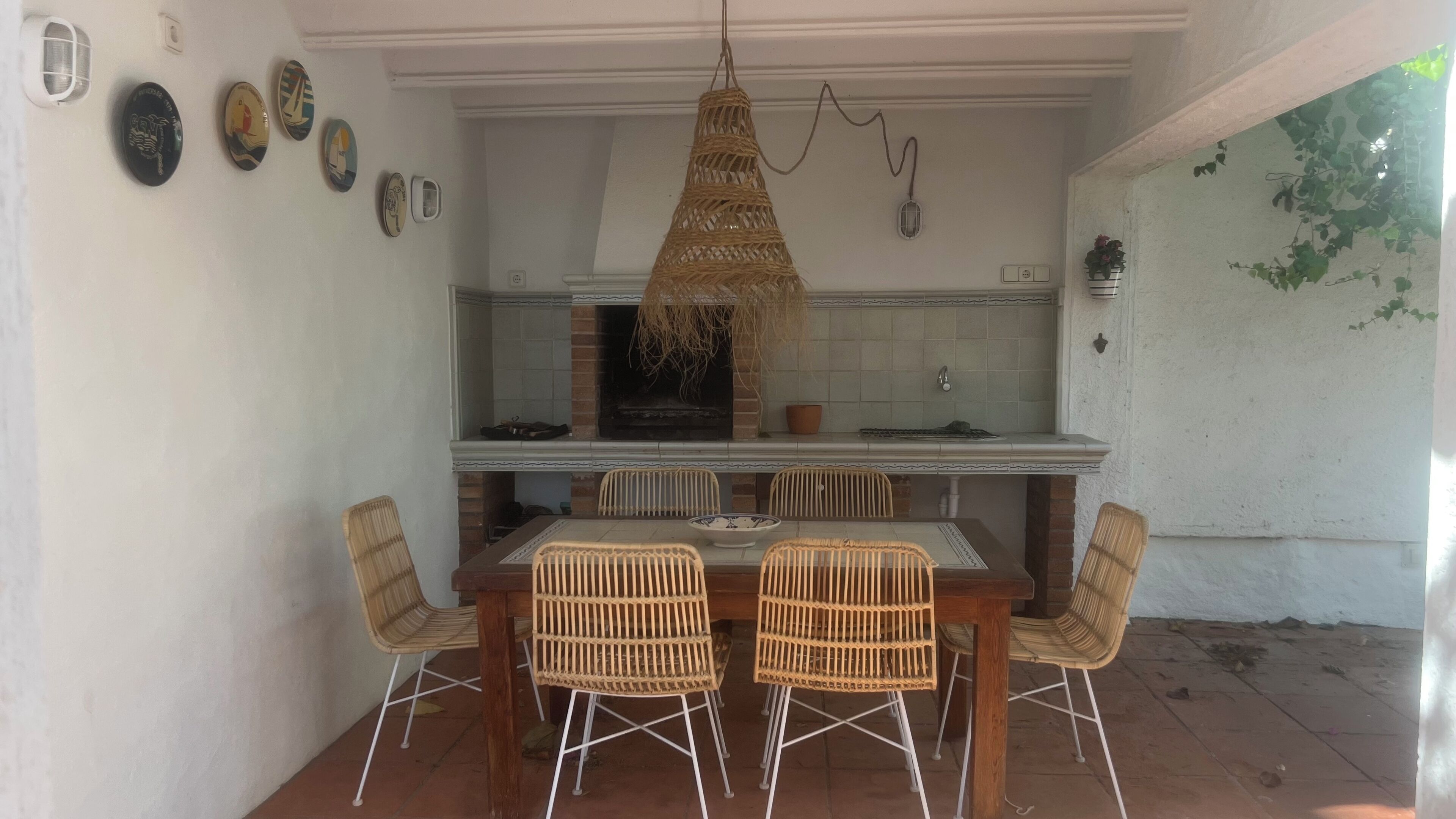 Una cocina con protector mural de ladrillo, paredes con azulejos blancos y una lámpara colgante.