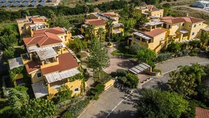 A residential area with yellow buildings, solar panels, and a central paved area.