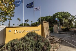 A yellow wall with the text "Porto degli Argonauti" and multiple flags.
