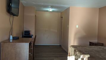 A hotel room with a wooden desk, a bed, and a television mounted on the wall.