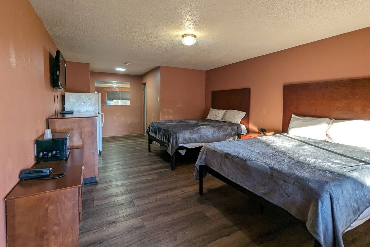 Une chambre d’hôtel avec deux lits, un bureau avec un téléphone et un petit coin cuisine.