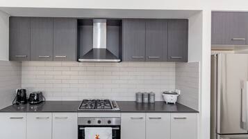 Modern kitchen with a stainless steel range hood, oven, and refrigerator.