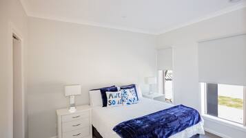 Relax in a serene bedroom with a neatly made bed, bedside table, and large window offering a view of the outdoors.