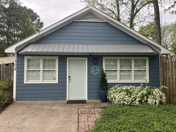 A single-story house with a white door and windows, a small porch, and a mailbox.