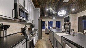 Een moderne keuken met roestvrijstalen apparatuur, een centraal eiland en een houten plafond.