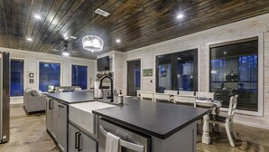 Een moderne keuken met een groot eiland, inbouwapparatuur en een eethoek met een bank en stoelen.