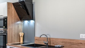 A modern kitchen with a built-in oven, a stainless steel sink, and a wooden backsplash.