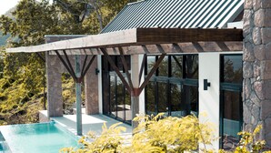 A modern outdoor pool area with a pergola structure, stone pillars, and a clear view of the surrounding landscape. - Enclave Villa V3 -Overlooking Pitons & Ocean ! Wow.  (Soufriere)