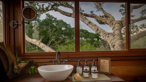 A bathroom with a large window, a white sink, and a mirror. - Alta Sanctuary (Tambopata)