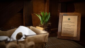 A framed informational sign about eco-friendly waste disposal in a rustic setting with wooden walls and a plant. - Alta Sanctuary (Tambopata)