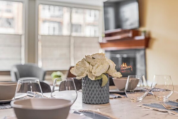 A dining table set with plates, glasses, and a vase of flowers. - ALPS Guesthouse at Solara Resort and Spa (Canmore)