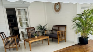 A covered outdoor seating area with wooden furniture and a potted plant. - Bienvenue à la Maison D'hôtes L'instant Present (Le Moule)