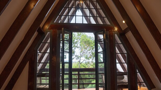 Un dormitorio en el ático con techo de madera, una cama grande y vistas al exterior.