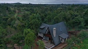 Una casa moderna con techo inclinado, rodeada de un bosque denso.