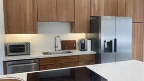 Une cuisine moderne avec des meubles en bois, des appareils en acier inoxydable, un four encastré et une machine à café.
