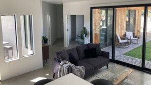 Un salon moderne avec un canapé gris, une table basse en verre et un ventilateur de plafond.