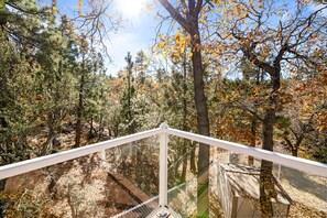 A forested area with a wooden deck and railing. - Luxurious Hyes in the Woods (Big Bear City)