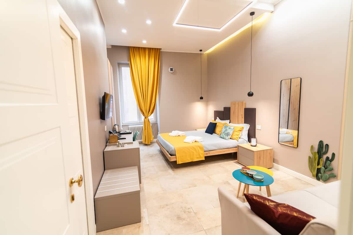 Un dormitorio moderno con cama, mesita de noche y un pequeño rincón de estar con mesa y sillas.