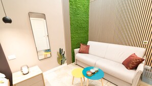 A modern living room with a white sofa, two small round tables, a mirror, and a green wall feature. - B&Bio Architiello (Naples)