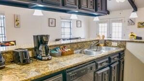A kitchen with granite countertops, a coffee maker, a toaster, and a dishwasher.