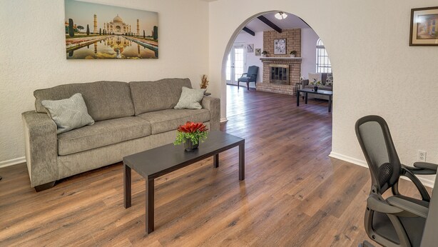 A living room with a sofa, a coffee table with a flower, and a painting of the Taj Mahal.