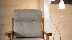 A wooden chair with a grey cushion, a remote control on a wooden table, and a floor lamp with a white shade. - L'écrin, Appartement aux Pieds des Pistes (Orcières)