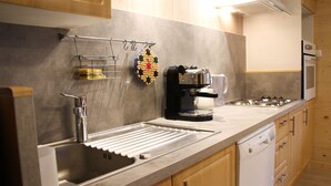 A modern kitchen with a stainless steel sink, a coffee maker, and wooden cabinets. - L'écrin, Appartement aux Pieds des Pistes (Orcières)