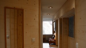 A wooden interior hallway with a wooden door, a bench, and a window at the end. - L'écrin, Appartement aux Pieds des Pistes (Orcières)