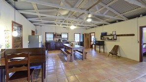 Una cocina amplia con armarios de madera, una mesa de comedor con bancos y un techo alto con vigas a la vista.