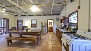 Una cocina amplia con una gran mesa de comedor, estufa a gas y refrigerador.